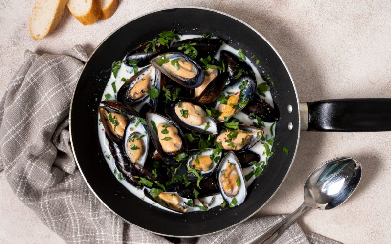 Top view pan with sauce and mussels